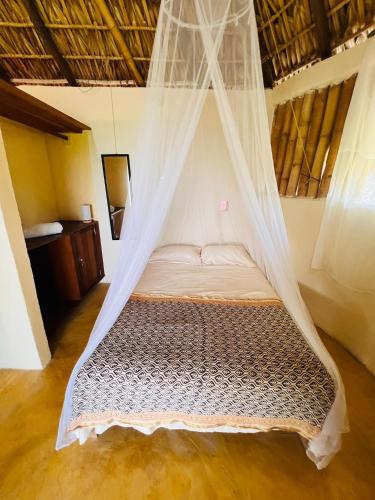 a bed in a room with a mosquito net at Columpio del Reptil cabaña in Mazunte