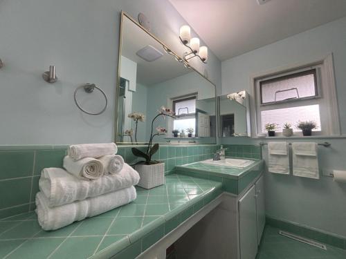 a green bathroom with a sink and a mirror at Charming Bright 3BR House - Upper Level Suite in Burnaby
