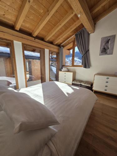 a large bed in a room with windows at Chalet Beaufort in Saint-Martin-de-Belleville