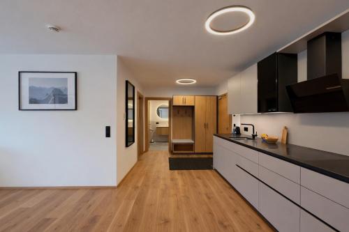 Una cocina con gabinetes blancos y encimeras negras. en Panorama Zillertal Loft - AlpenLuxus Colleciton, en Größing