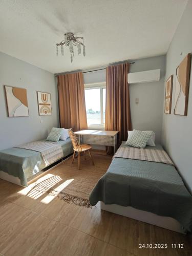 a bedroom with two beds and a chair and a window at Brand New Townhouse with hotel infrastructure in Paphos