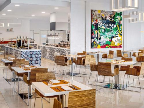 a restaurant with tables and chairs and a painting on the wall at Novotel Dubai Al Barsha in Dubai