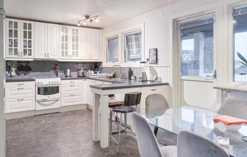 a kitchen with white cabinets and a glass table at 5 Bedroom Nice Home In Motala in Fornåsa
