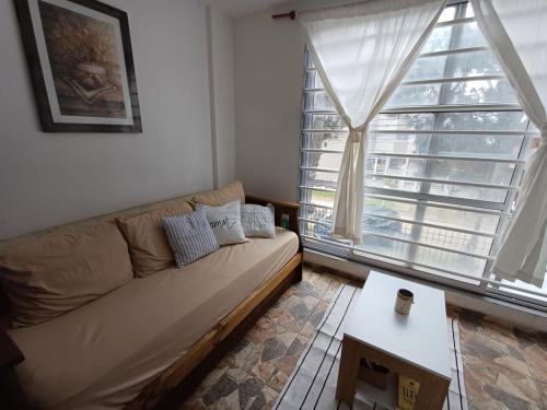 a living room with a couch and a large window at Depto Costa in San Bernardo