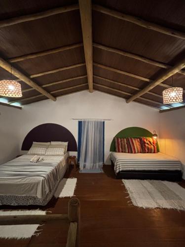 two beds in a room with wooden ceilings at Casinha do Por do Sol in Caraíva