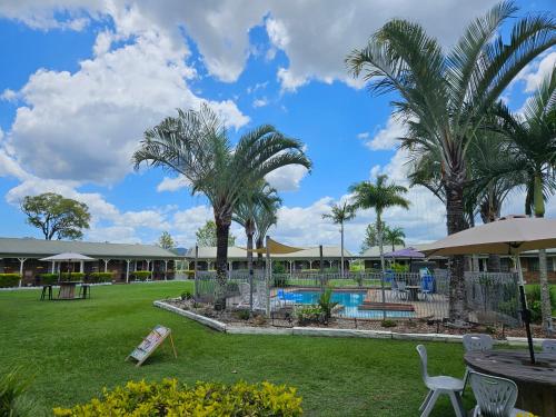 a resort with a swimming pool and palm trees at Koorawatha Homestead Motel in Bororen