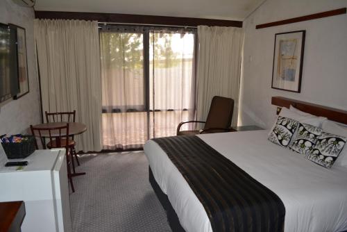 a hotel room with a bed and a table and chairs at The Apple Inn in Batlow