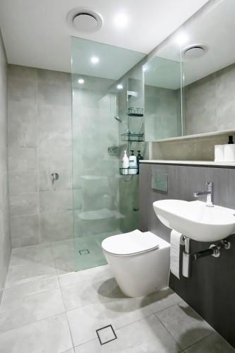 a bathroom with a toilet and a sink and a shower at Modern 2BR Apartment in Sydney Olympic Park in Sydney
