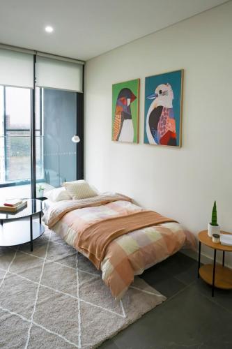 a bedroom with a bed and two paintings on the wall at Modern 2BR Apartment in Sydney Olympic Park in Sydney