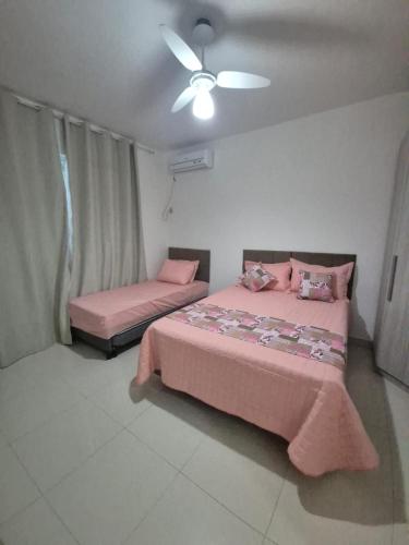 a bedroom with two beds and a ceiling fan at Elis Praia e Aconchego in Iguaba Grande