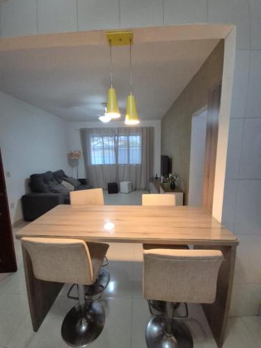 a large wooden table in a living room with chairs at Elis Praia e Aconchego in Iguaba Grande