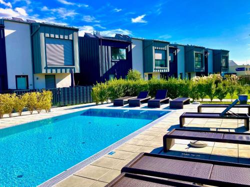 ein Swimmingpool mit Liegestühlen neben einem Haus in der Unterkunft SPA & SOUL Residence Neusiedl am See in Neusiedl am See