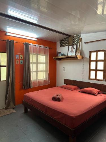 a bedroom with a red bed with two hats on it at M&M moanatea lodge in Rangiroa