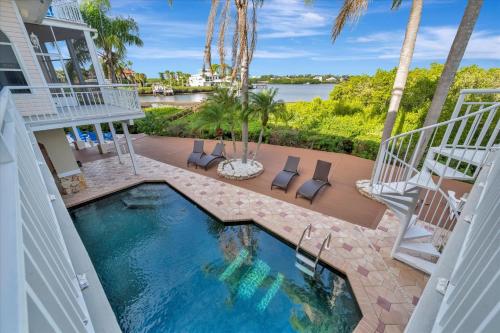 Blick auf einen Swimmingpool mit Palmen und einem Haus in der Unterkunft 4B Waterfront Game Room Pool Hot Tub Dock in Palm Harbor