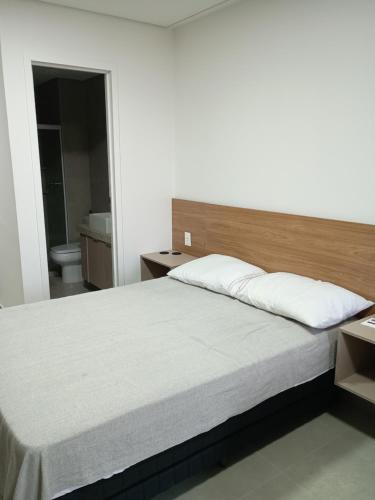 een slaapkamer met een groot bed met een houten hoofdeinde bij Studio Beach Class Summer em Porto de Galinhas PE in Porto De Galinhas