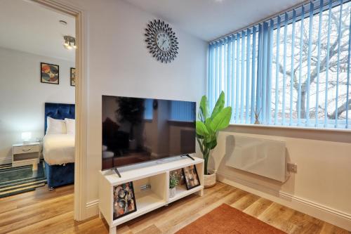 a living room with a large tv and a bedroom at Luxuriously Cosy 1 Bed Flat at Trinity Point Gravesend, Suitable for Long Stay and Short Stay in Gravesend