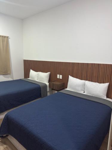 twee bedden in een hotelkamer met blauwe lakens bij Hotel Mochomos Huajuapan in Huajuapan de León