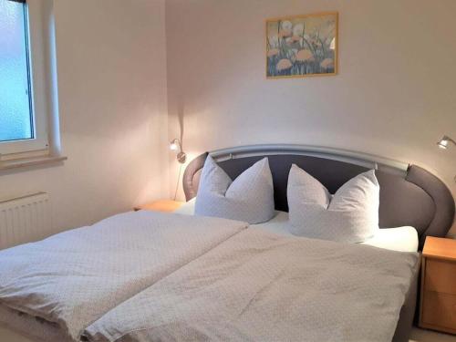 ein Schlafzimmer mit einem Bett mit weißen Laken und Kissen in der Unterkunft Holiday apartment in Parlow with parking in Parlow-Glambeck