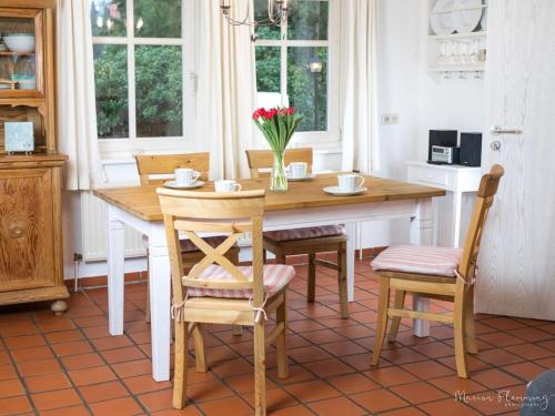 een keuken met een houten tafel met stoelen en een vaas met bloemen bij Romantic half-timbered house in Egestorf