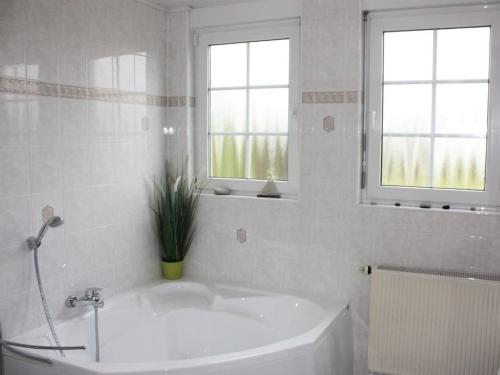 ein weißes Badezimmer mit einem Waschbecken und zwei Fenstern in der Unterkunft Holiday apartment with 3 bedrooms in Kördorf