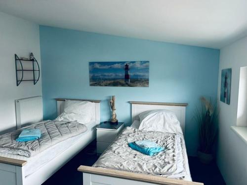 twee bedden in een kamer met een blauwe muur bij House 4seasons Scharbeutz in Scharbeutz