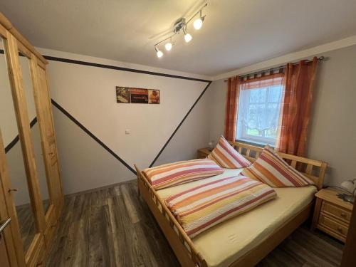 ein Schlafzimmer mit einem Bett mit gestreifter Bettwäsche und einem Fenster in der Unterkunft Seidl - Holiday Apartment in Laiflitz