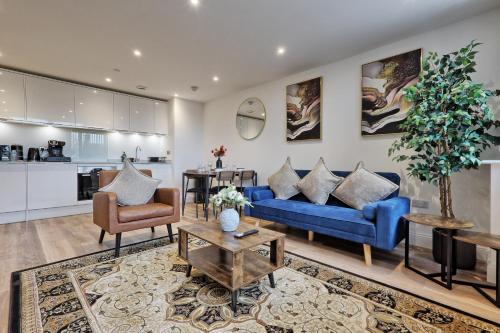 a living room with blue couches and a kitchen at Homely & Lush 1 Bed Apartment at Trinity Point Gravesend, Suitable for Long Stay and Short Stay in Gravesend
