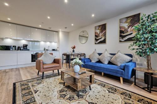 a living room with blue couches and a kitchen at Homely & Lush 1 Bed Apartment at Trinity Point Gravesend, Suitable for Long Stay and Short Stay in Gravesend