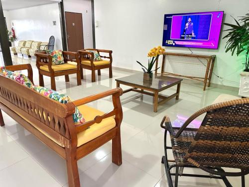 ein Wohnzimmer mit Stühlen und Tischen und einem Fernseher in der Unterkunft Hotel Alexânia in Alexânia