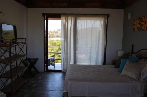 een slaapkamer met een bed en een grote glazen schuifdeur bij Mallki bungalows with pool in Vichayito