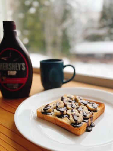 大町市フリーフロー付きB&B Lodge GRAMP的盘子里放着一块面包，旁边是一瓶咖啡。