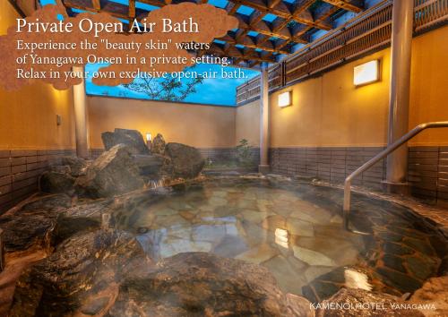 a large hot tub in a building with rocks at KAMENOI HOTEL Yanagawa in Yanagawa