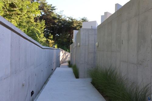 an alley between two concrete fences with trees at Buan Intaglio Pool Villa in Buan
