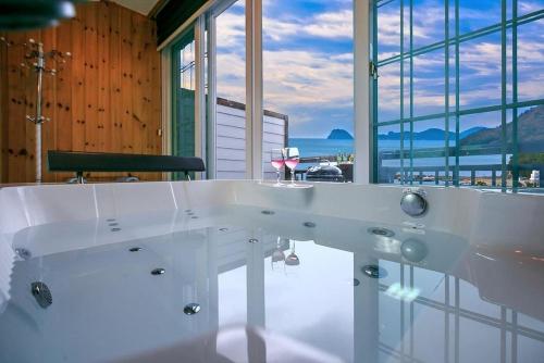 a white bath tub with a view of the ocean at Geoje Haneul Ari Pension in Geoje