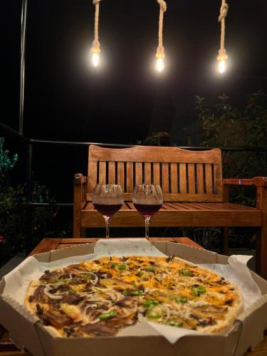 a pizza in a box with two glasses of wine at Chalé em Parque Aquático - Presidente Figueiredo in Presidente Figueiredo