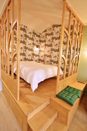 a bedroom with a bed in a wooden frame with a green seat at Élégant studio à Tournus - logement moderne et bien situé - ROGER in Tournus