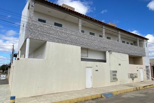 a white building with a gray roof on a street at Flat aconchego PNz in Petrolina