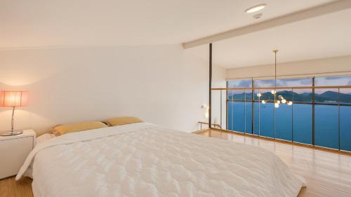 une chambre blanche avec un lit et une grande fenêtre dans l'établissement Namhae Ourpoolvilla, à Namhae