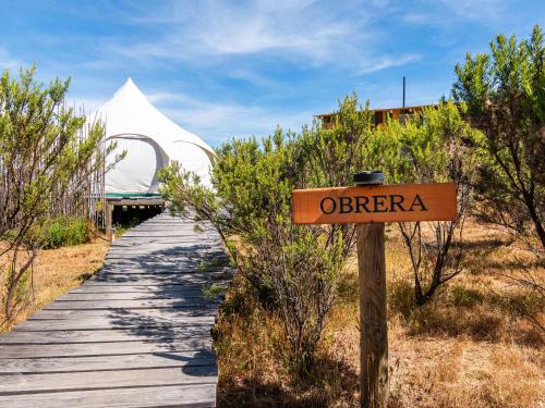 El RosarioLa Colmena Glamping Obrera的一条木板路，路牌上写着“otario”。
