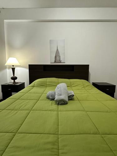 a bed with a green comforter and two towels on it at Espacio necochea in Mendoza