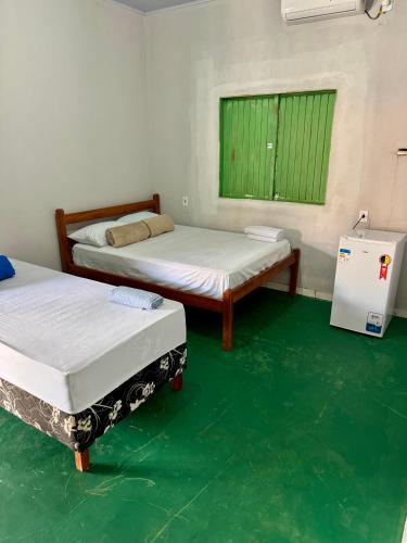 two beds in a room with green floors and a window at Pousada e Camping São José in Manhã