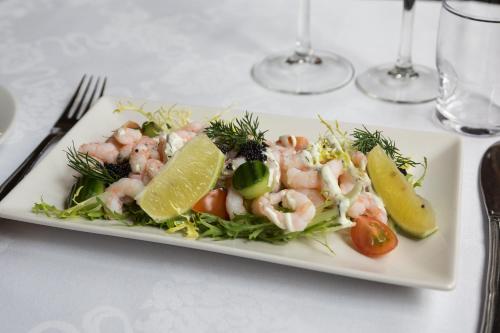 a white plate with shrimp and vegetables on a table at Helnan Phønix Hotel in Aalborg