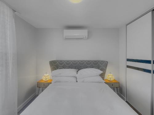 ein Schlafzimmer mit einem Bett mit weißen Laken und Kissen in der Unterkunft Spacious Modern Apartment in Batemans Bay in Batemans Bay