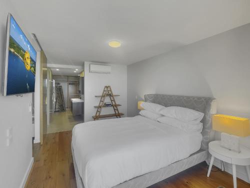 ein Schlafzimmer mit einem weißen Bett und einer Leiter in der Unterkunft Spacious Modern Apartment in Batemans Bay in Batemans Bay