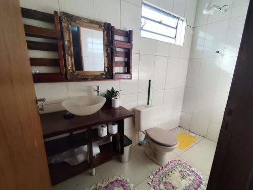 a bathroom with a sink and a toilet and a mirror at Casa Aconchego da Vó Gera in Foz do Iguaçu