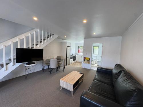 a living room with a black leather couch and a table at Camellia Court Motel in Lower Hutt