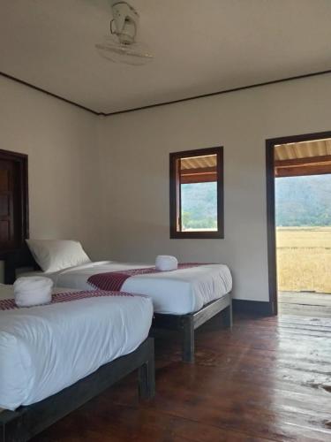 two beds in a room with two windows at Guesthouse and Restaurant SayLomYen KongLor in Ban Dôn