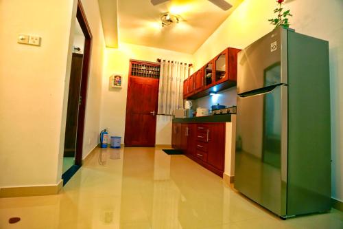 a kitchen with a green refrigerator and wooden cabinets at Orchidee Apartments in Mount Lavinia