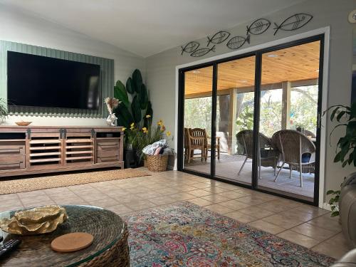 ein Wohnzimmer mit einem TV und einer Glasschiebetür in der Unterkunft Natures Nest Waterfront in Homosassa