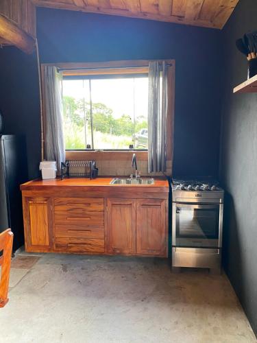 a kitchen with a stove and a sink and a window at Cabana Rústica em Piedade in Piedade